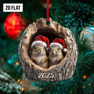 May include: A Christmas ornament featuring two squirrels wearing Santa hats, nestled in a wooden log. The hats are inscribed with the names "Daniel" and "Jessica." The year "2025" is displayed at the bottom. The ornament is hanging from a red ribbon.