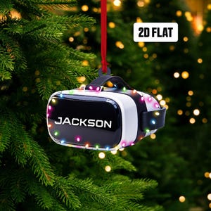 May include: A black and white virtual reality headset with a red string attached to the top. The headset is decorated with colorful Christmas lights and the word "JACKSON" is printed on the front.