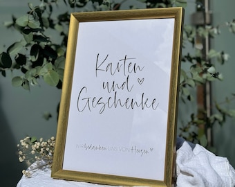 May include: A gold-framed sign with white background and black text that reads "Karten und Geschenke" and "Wir bedanken uns von Herzen".