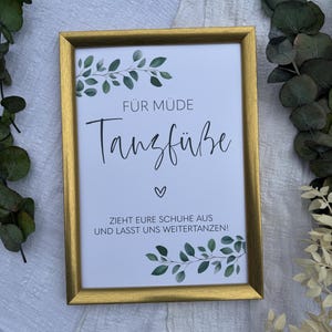 Könnte beinhalten: Ein goldfarbener Rahmen mit grünen Blättern und dem Text "FÜR MÜDE Tanzfüße" und "ZIEHT EURE SCHUHE AUS UND LASST UNS WEITER TANZEN!"