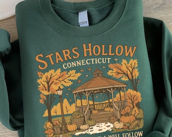 May include: Dark green sweatshirt featuring a fall-themed graphic with a gazebo, pumpkins, and the text "Stars Hollow Connecticut Where You Lead I Will Follow." The design is in shades of orange, brown, and yellow.