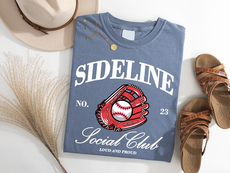 May include: A blue t-shirt with the text "Sideline Social Club" in white, a red baseball glove with a white baseball, and the text "No. 23" in white. The text "Loud and Proud" is also in white.