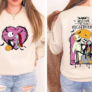 May include: Beige sweatshirt featuring a pink heart design with Jack Skellington and Sally. The back of the sweatshirt has the text "WELCOME TO OUR NIGHTMARE" with Jack, Sally, and Oogie Boogie. Bats and pumpkins are also featured.
