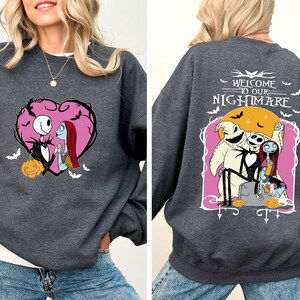 May include: Dark gray sweatshirt featuring a heart-shaped graphic with Jack Skellington and Sally. The back of the sweatshirt has the text "WELCOME TO OUR NIGHTMARE" with characters from the movie. A Halloween-themed apparel item.