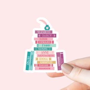 May include: A sticker featuring a stack of colorful books with names like Elizabeth, Darcy, and Emma. A teal inkwell with a feather sits atop the books. The sticker is held by a hand against a pink background.