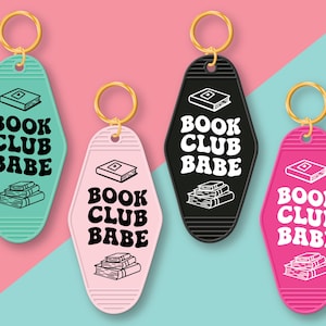 May include: Four keychains with a motel key design. Each keychain has a black and white graphic of a stack of books and the text "Book Club Babe". The keychains are in four different colors: teal, pink, black, and hot pink.