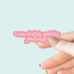 May include: A pink sticker with the text "*immediately updates goodreads*" in white script. The sticker has a scalloped edge and is held against a light blue background.