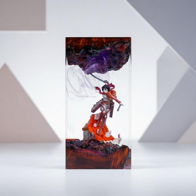 Puede incluir: Escultura de resina que presenta una figura de anime con una espada, sobre una base texturizada marr&oacute;n rojizo. Elementos morados y blancos arremolinados completan la escena, todo encerrado en un bloque rectangular transparente.