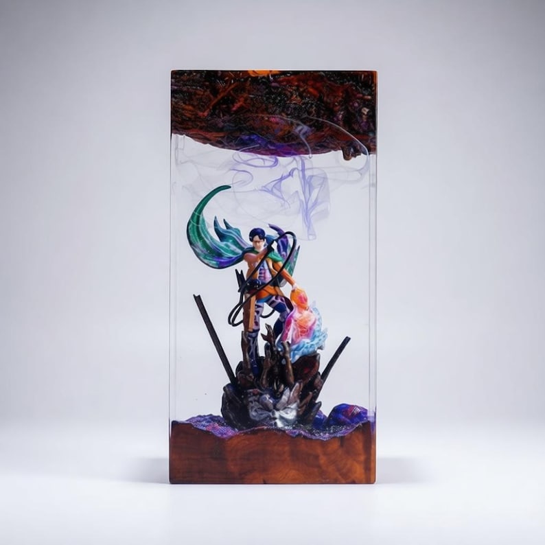 Puede incluir: Escultura rectangular de resina con dos figuras en una pose din&aacute;mica, encapsuladas en resina transparente. La escultura tiene una base de madera y una parte superior oscura y texturizada. Las figuras est&aacute;n detalladas con colores vibrantes, la resina tiene un efecto ahumado.