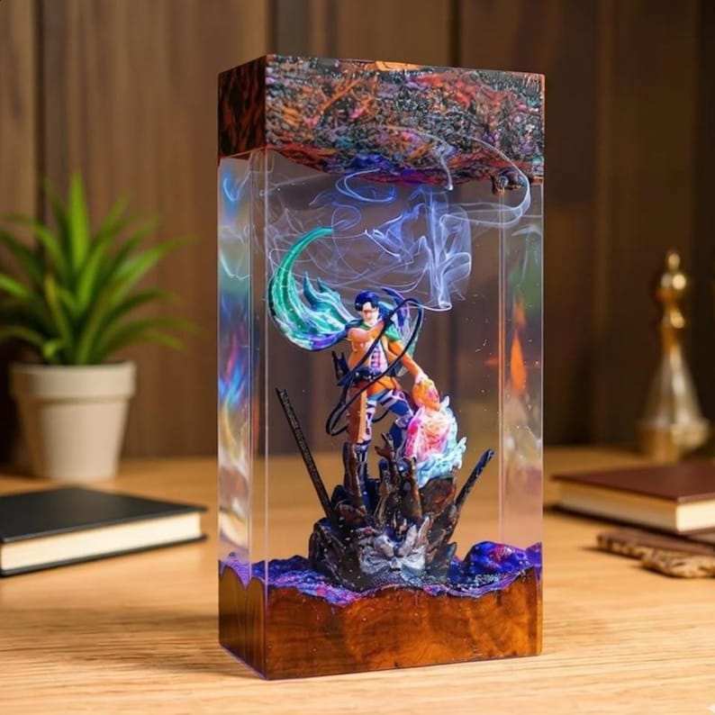 Puede incluir: Una pieza de arte de resina rectangular con una figura en su interior. La figura es de un personaje con cabello azul y un atuendo naranja, de pie sobre una base oscura. La resina tiene una base y parte superior de madera, con remolinos coloridos y efectos de humo.