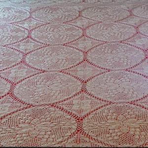 Può includere: Copriletto color crema con motivo floreale rosso. Il motivo presenta forme ovali con dettagli floreali. Il copriletto è posizionato su una struttura letto nera.