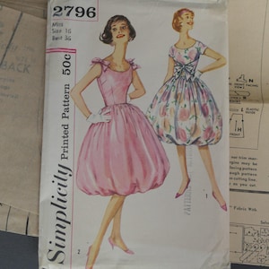 Peut inclure: Patron de couture Simplicity vintage, taille 16, avec des illustrations de deux robes. L'une est une robe rose bouffante, l'autre une robe bouffante à imprimé floral. Le patron est marqué 2796 et comprend des instructions.