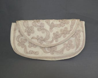 May include: Off-white clutch with a curved flap, adorned with embroidered floral patterns in a muted mauve color. The embroidery creates a textured surface, adding visual interest to the accessory.