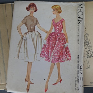 Op de afbeelding: Vintage McCall's gedrukt naaipatroon met illustraties van twee jurken en een jasje. Het patroon bevat een jurk met een bloemenprint en een jurk met een witte rok en bruine top. Het patroonnummer is 5417.