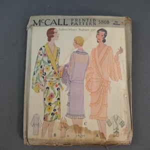 May include: A vintage McCall Printed Pattern 5808 envelope for a negligee. The front features illustrations of three robe styles: one with a floral print and yellow collar, one in solid lavender, and one in peach with ruffled trim and sleeves.