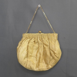 May include: A vintage gold mesh handbag with a chain handle. The purse has a gathered design and a clasp closure. The chain is also gold-toned, and the bag hangs against a gray background.
