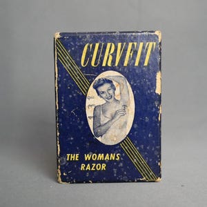 Puede incluir: Caja de afeitadora "CURVFIT" vintage. La caja azul marino presenta el texto "CURVFIT" en amarillo, con una ilustración vintage de una mujer. El texto "THE WOMANS RAZOR" está impreso en la parte inferior de la caja.