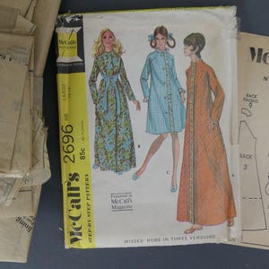 May include: Vintage McCall's sewing pattern for Misses' robes in three versions. The pattern envelope features illustrations of the robes, with the number 2696 and the price 85c. Includes pattern pieces and instructions.