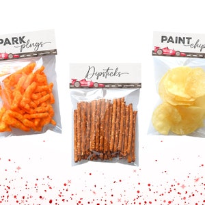 May include: Three clear plastic bags with labels and snacks. The labels are red, white, and black with a cartoon race car. The labels read "Spark Plugs", "Dipsticks", and "Paint Chips". The bags contain orange cheese puffs, pretzel sticks, and potato chips.