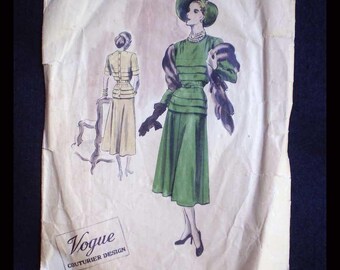 May include: A vintage Vogue sewing pattern envelope, number 398, featuring a fashion illustration of a person in a green dress, hat, and stole, with a smaller back view of the garment in beige. The text reads Vogue Couturier Design.