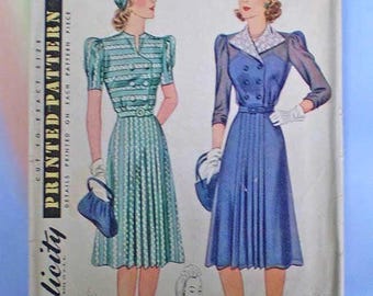 May include: A vintage Simplicity sewing pattern envelope featuring illustrations of two dresses. One dress is teal with horizontal stripes and short sleeves, the other is solid blue with long sheer sleeves and a white collar. Both include matching hats.