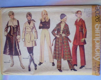 May include: A vintage Simplicity sewing pattern envelope 9026 featuring illustrations of five outfits including a brown faux fur trimmed coat, a beige belted coat, a dark sweater with light trousers, a plaid coat with pants, and a red coat with pants.