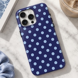 May include: A dark navy blue smartphone case featuring a repeating pattern of light baby blue polka dots. The case has a rectangular shape with rounded corners and a square cutout in the upper left corner for a triple-lens camera system.