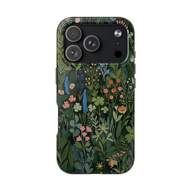 Pu&ograve; includere: Una custodia per smartphone con sfondo verde scuro e un denso motivo botanico di fiori selvatici, foglie e steli in tonalit&agrave; rosa, blu, arancione e verde chiaro, che circonda l'area nera del modulo fotocamera.