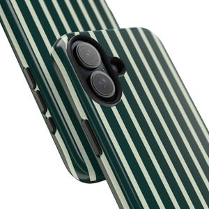 Może przedstawiać: Zbliżenie dw&oacute;ch etui na telefon z pionowym wzorem w paski. Etui są ciemnozielone z kremowymi paskami. G&oacute;rne etui ma obiektyw aparatu i przyciski boczne.