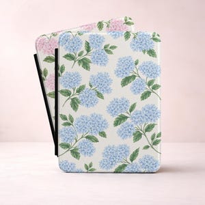 May include: A rectangular e-reader case featuring a repeating pattern of light blue hydrangea flower clusters with green leaves on a white background, with a secondary pink hydrangea pattern visible on the partially opened inner cover.