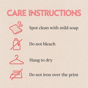 May include: A care instructions graphic with pink text and icons. It lists: Spot clean with mild soap, Do not bleach, Hang to dry, and Do not iron over the print. Each instruction is paired with a corresponding pink line-art icon of a sponge, a bottle, a hanger, and an iron.