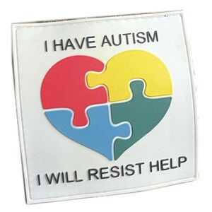 Pode incluir: Patch quadrado branco com o texto "Tenho autismo" e um design de peça de quebra-cabeça em forma de coração em vermelho, amarelo, azul e verde. O texto "Vou resistir à ajuda" está na parte inferior do patch.
