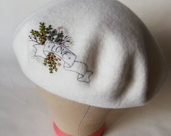 Ecru dikke wolvilt baret, handgeborduurd met banner met liefdesletters, met delicate bloemen en gebladerte