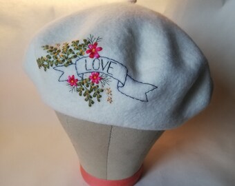 Ecru dikke wolvilt baret, handgeborduurd met LOVE-banner, bloemen- en loofpatroon