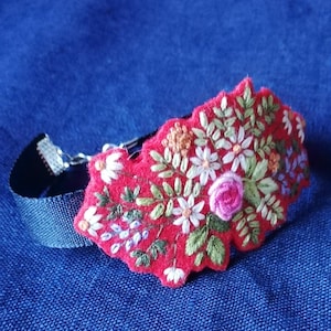 Embroidered floral and foliage bracelet ribbon and felt with a cut edge.
