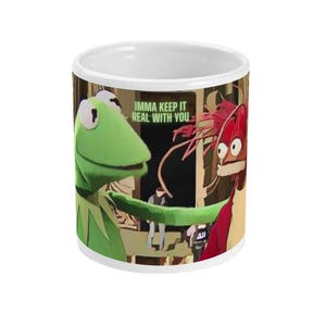 May include: White ceramic mug featuring a green frog and a red lobster puppet. The frog is saying "Imma keep it real with you".