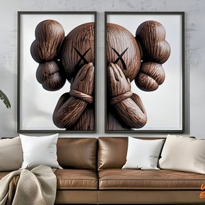 May include: A pair of framed prints featuring a wooden sculpture of a character with its hands covering its eyes. The sculpture is brown and has a wood grain texture. The background is white.