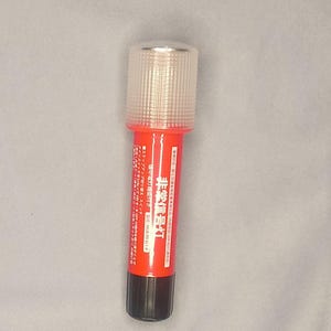 May include: A red and black emergency flare with a clear, ridged top. The flare has Japanese text on the side and is designed to be a safety device. The top is a clear, ridged plastic.
