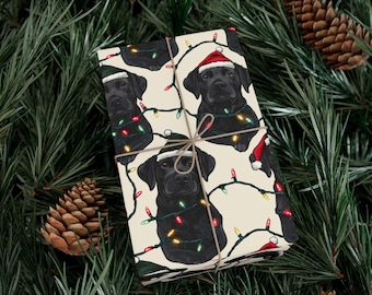 Pode incluir: Papel de embrulho de Natal com um Labrador Retriever preto usando um chapéu de Papai Noel e rodeado de luzes de Natal coloridas.