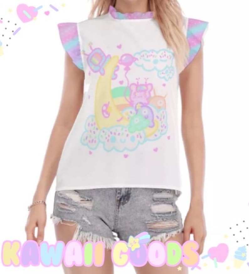 May include: White sleeveless top featuring a pastel cartoon graphic of a moon, clouds, and characters. The top has ruffled sleeves with pastel colours and a ruffled neckline. The text "KAWAII GOODS" is at the bottom.