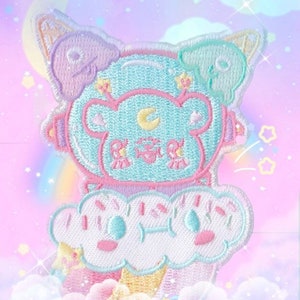 May include: Embroidered patch with a cartoon bear in a space helmet design. The patch is light blue, pink, and purple, with a cloud and ice cream cone base. The text "KAWAII GOODS" is at the bottom.