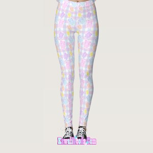 May include: Pink, blue and yellow leggings with a gingham pattern and cartoon bears. The leggings are on a white background.