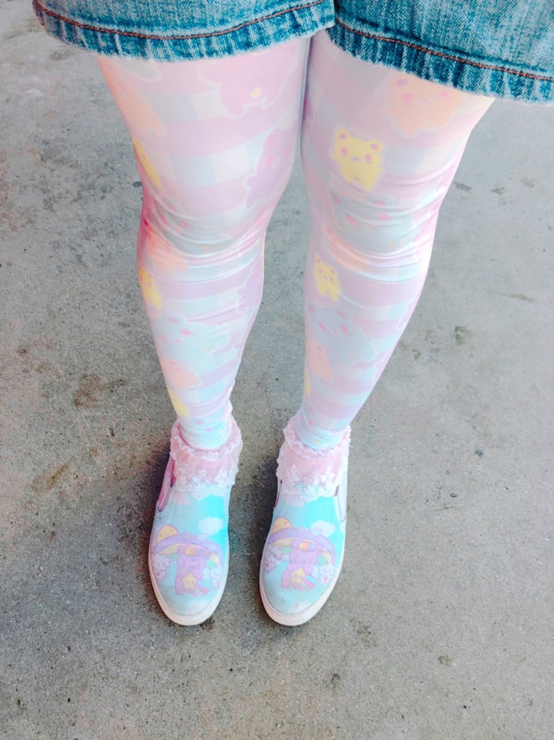 May include: A pair of pastel blue and pink patterned tights with a cartoon character design. The tights are worn with a pair of white canvas shoes with a cartoon character design.