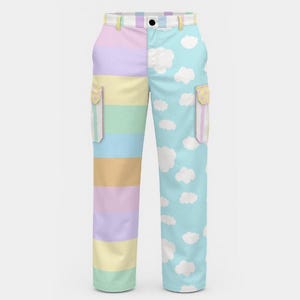 Puede incluir: Pantalones cargo de colores pastel. Un lado presenta rayas horizontales en tonos rosa, amarillo, verde y azul. El otro lado tiene un fondo azul claro con patrones de nubes blancas. Los pantalones tienen dos bolsillos y cierre de botón.