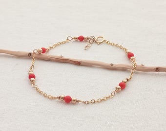 Puede incluir: Un delicado brazalete de cadena dorada con pequeñas cuentas rojas. El brazalete tiene un cierre de mosquetón.