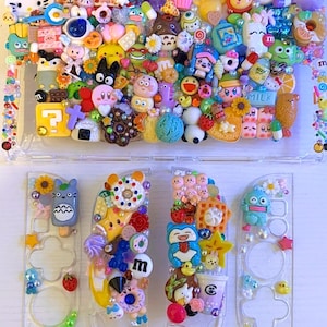 May include: Clear plastic Nintendo Switch case and controllers, adorned with numerous colourful, miniature, cartoon-themed charms. The case and controllers feature various shapes, including donuts, stars, and character figures.
