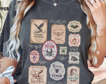 May include: Dark gray t-shirt with various vintage-style potion labels. Labels include "Phoenix Feathers," "Love Potion," "Poison," "Black Venom," and "Unicorn Blood." The shirt has the word "PEPPER" printed on the upper left.