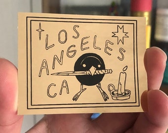 Los Angeles, CA Bird with Knife Black on Gold Foil Sticker by Deth P. Sun