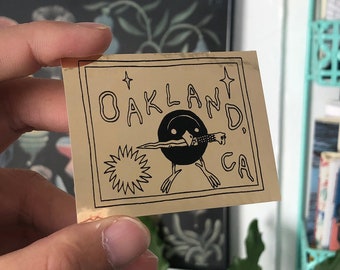 Oakland Bird with Knife Black on Gold Foil Sticker by Deth P. Sun