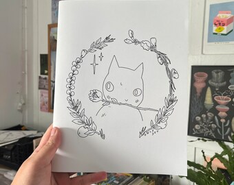 Puede incluir: Un dibujo en blanco y negro de un gato con una flor en la boca, rodeado de una corona de hojas y flores. El texto "Only You" está escrito debajo del gato.
